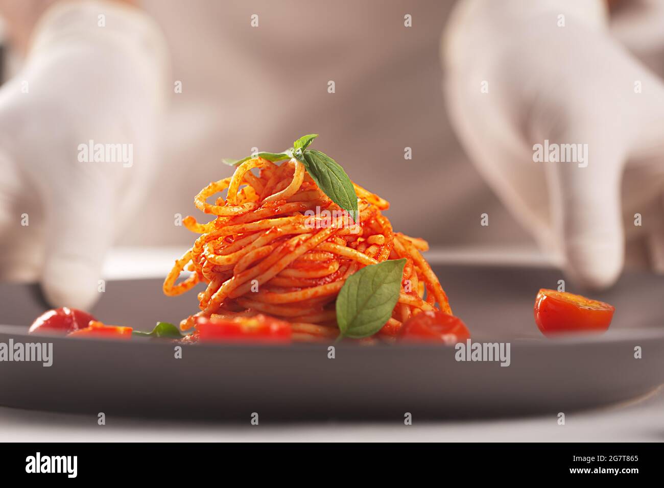 Lo chef tiene un piatto di pasta in salsa di pomodoro nelle mani gugorate. Serve alta cucina, piatti Foto Stock