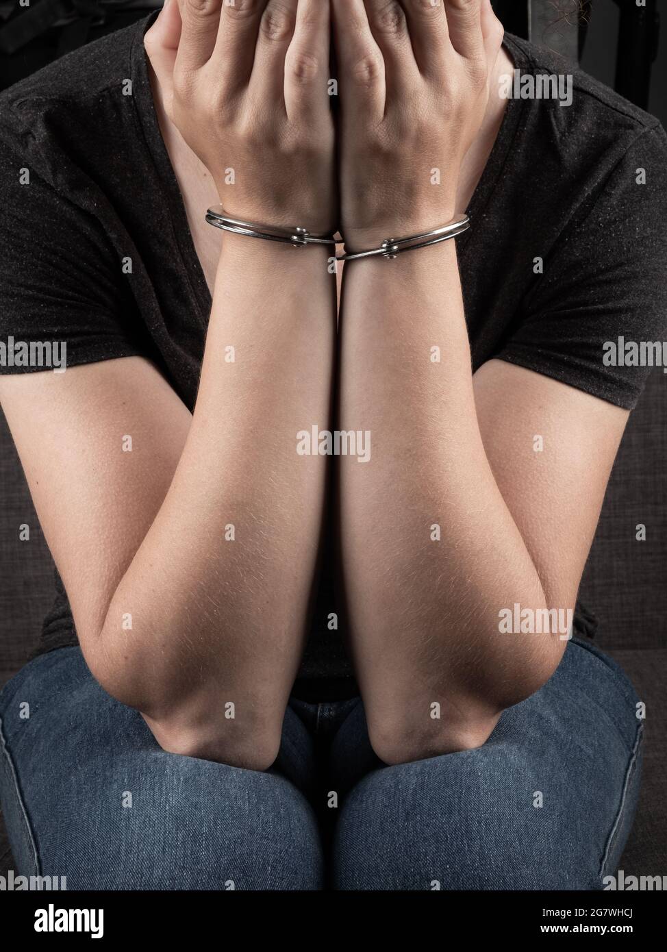 donna in manette coperto il viso e si rammarica del crimine. Foto Stock