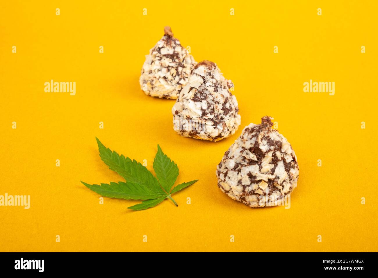 caramelle al cioccolato con noci e marijuana su sfondo giallo. cibo con cannabis ricreativa. Foto Stock
