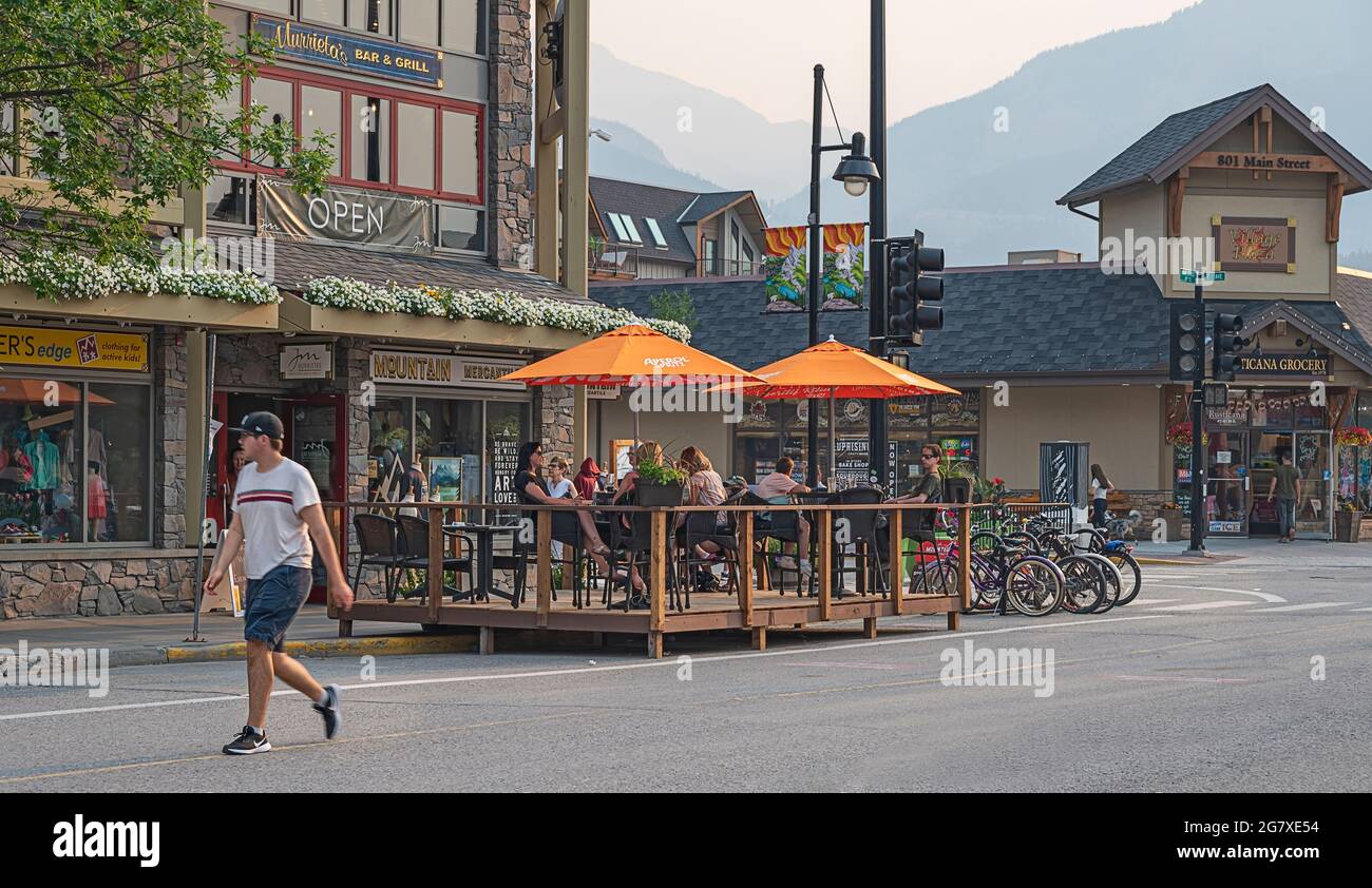 Canmore, Alberta, Canada – 14 luglio 2021: Vista serale di Main Street con un patio ristorante, persone e negozi Foto Stock