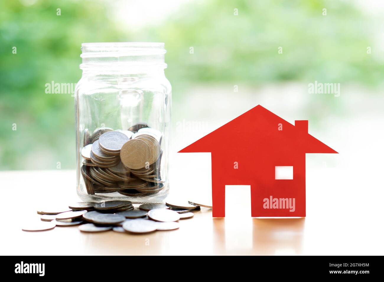 Monete in vaso con red house. Il risparmio per home concetto Foto Stock