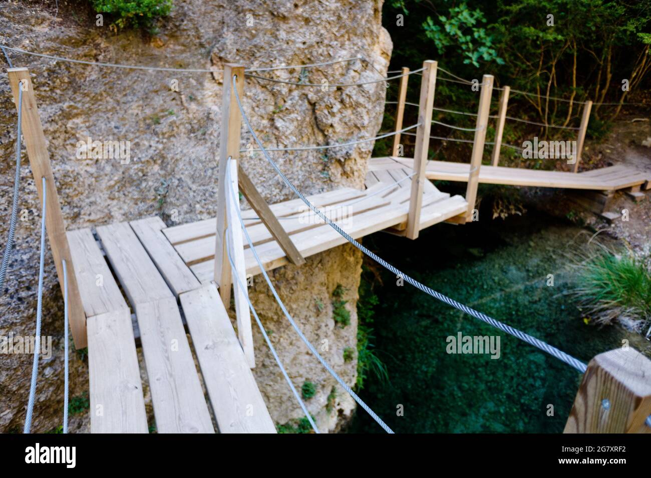 Passerella in legno accanto ad alcune rocce sul letto di un fiume per facilitare il passaggio di turisti e escursionisti. Foto Stock
