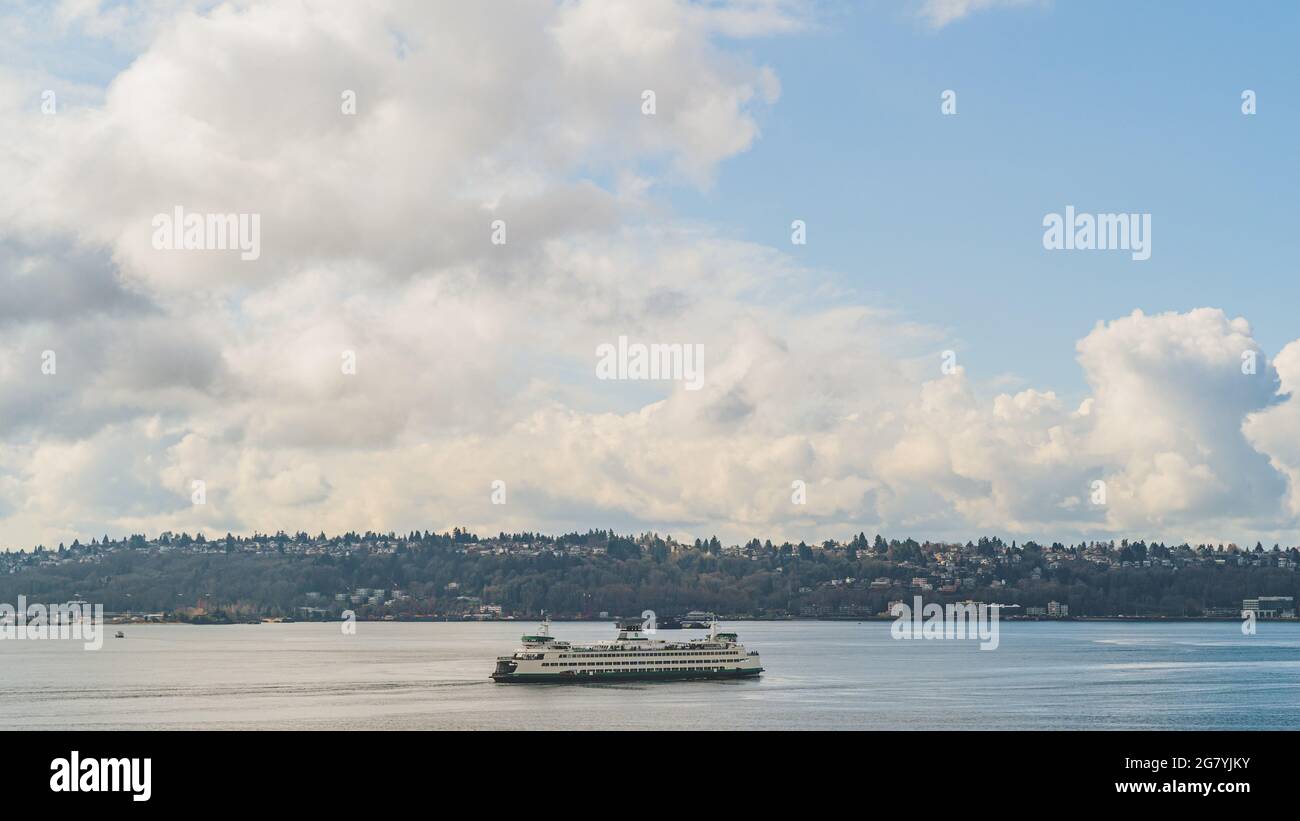 Washington Ferry naviga su Elliot Bay con West Seattle e Cloud Sky background Foto Stock