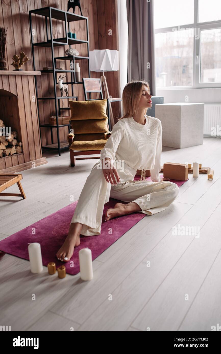 Bella giovane calma donna meditating rilassante seduta su tappetino naturale in casa accogliente interno nel fine settimana. Benessere della donna. Foto di alta qualità Foto Stock