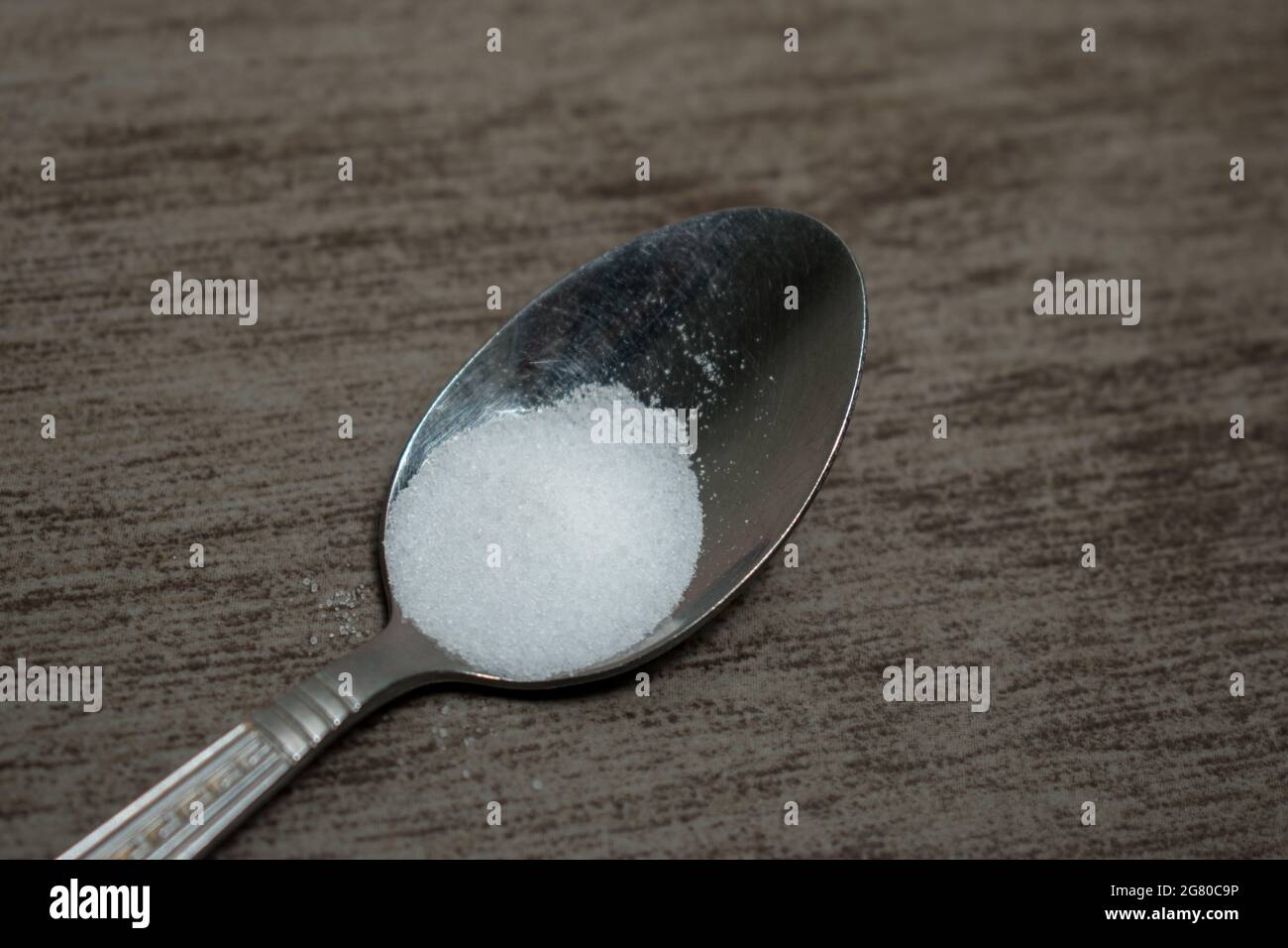 Primo piano di un po' di sale su un cucchiaio d'argento su un tavolo di  legno Foto stock - Alamy