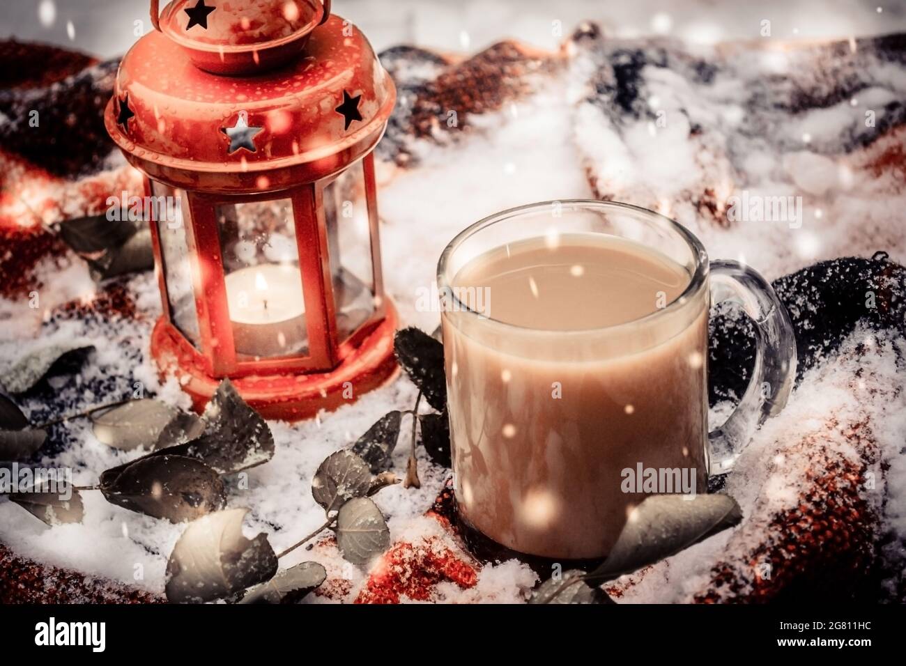 Candela rossa festosa in lanterna e tazza di caffè su tappeto con neve Foto Stock