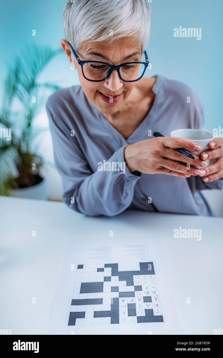 Donna anziana che risolve il puzzle crossword Foto Stock