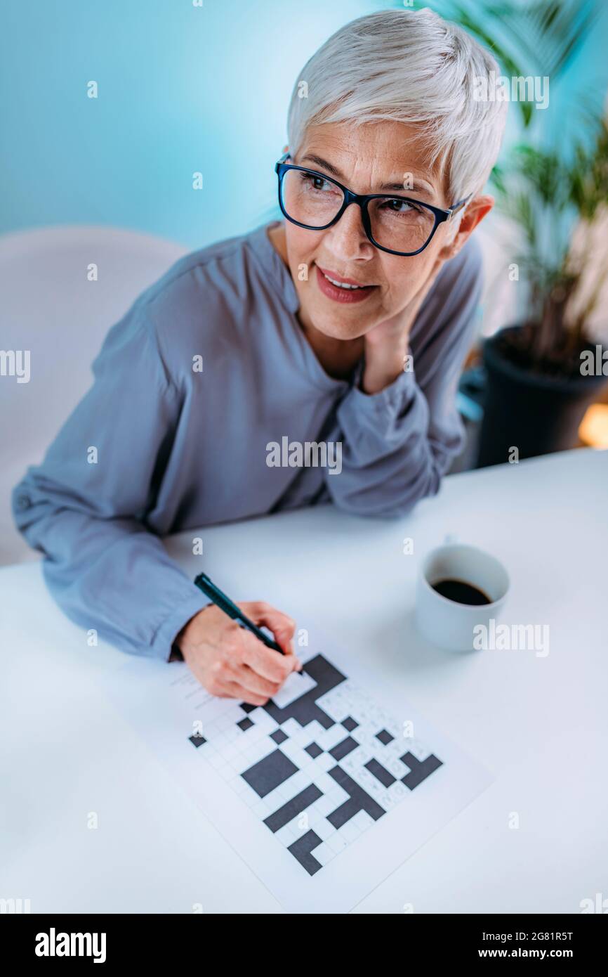 Donna anziana che risolve il puzzle crossword Foto Stock