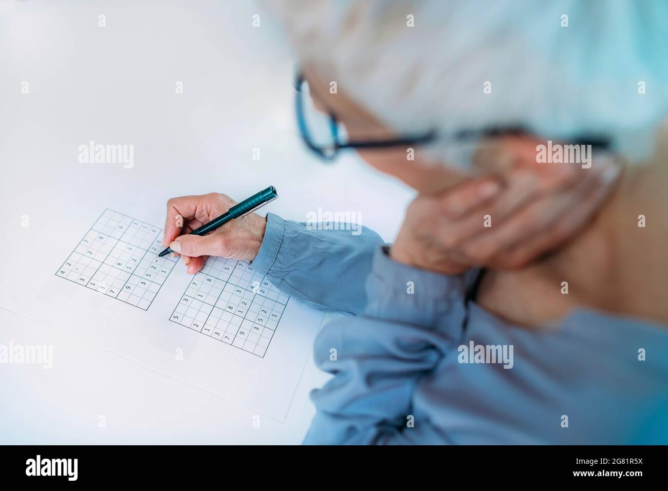 Donna anziana che risolve il puzzle sudoku Foto Stock