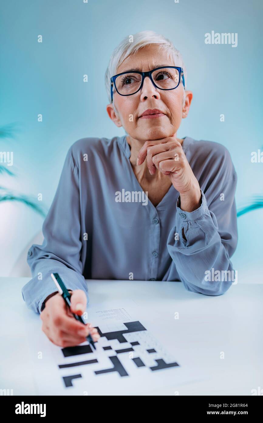Donna anziana che risolve il puzzle crossword Foto Stock