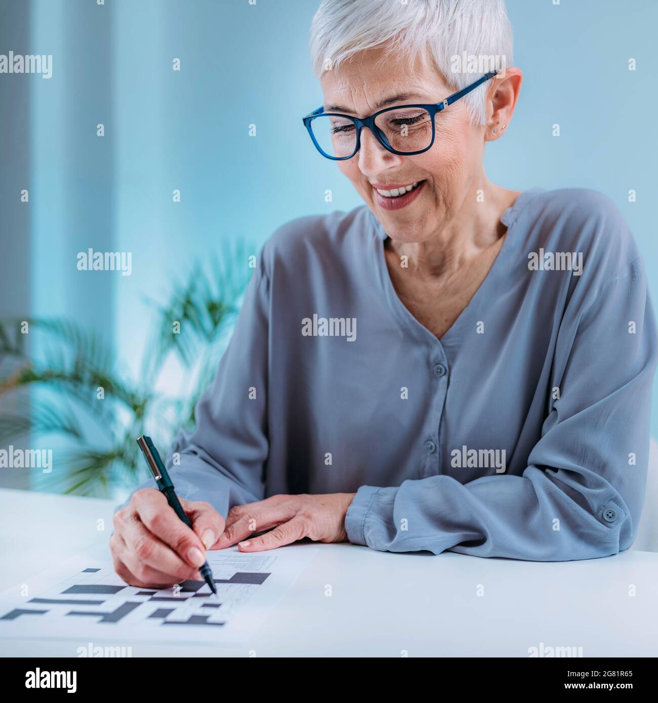 Donna anziana che risolve il puzzle crossword Foto Stock