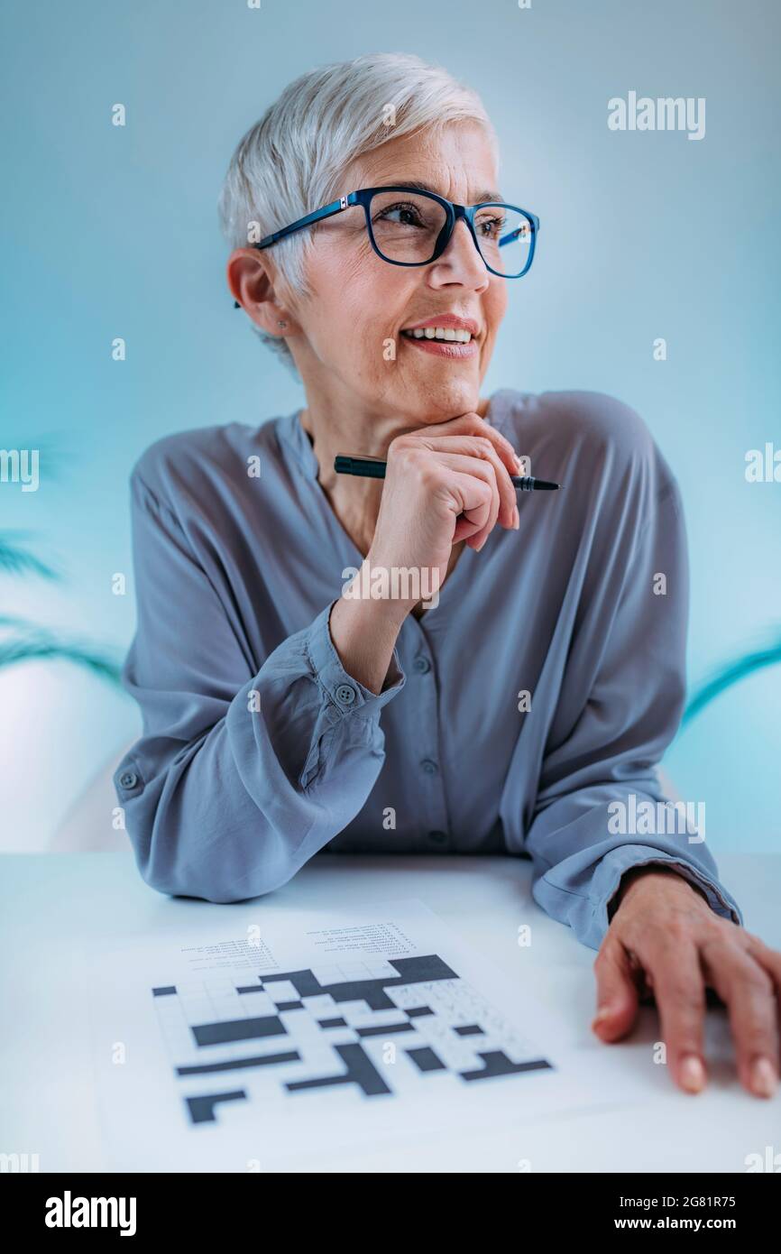 Donna anziana che risolve il puzzle crossword Foto Stock