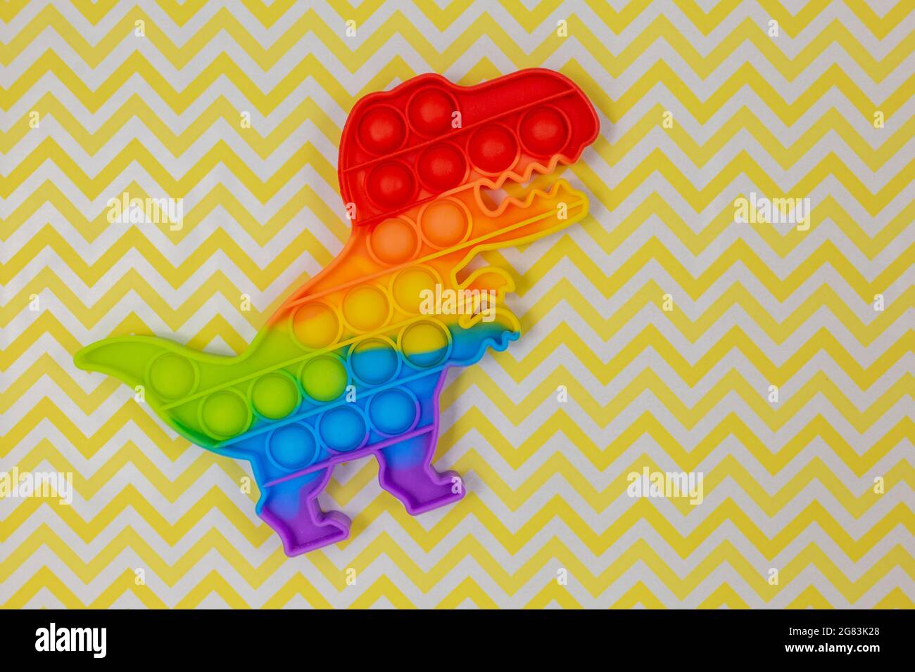 Popolari giocattoli in silicone anti-stress pop-it per un bambino su sfondo giallo. Trendy reliever stress sensoriale Fidget Toy per bambini e adulti Foto Stock