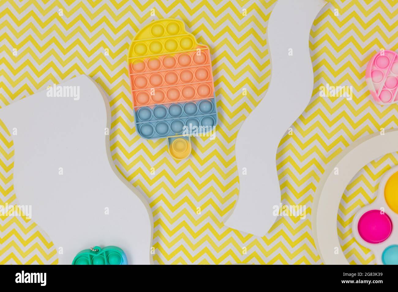 Popolari giocattoli in silicone anti-stress pop-it per un bambino su sfondo giallo. Trendy reliever stress sensoriale Fidget Toy per bambini e adulti Foto Stock