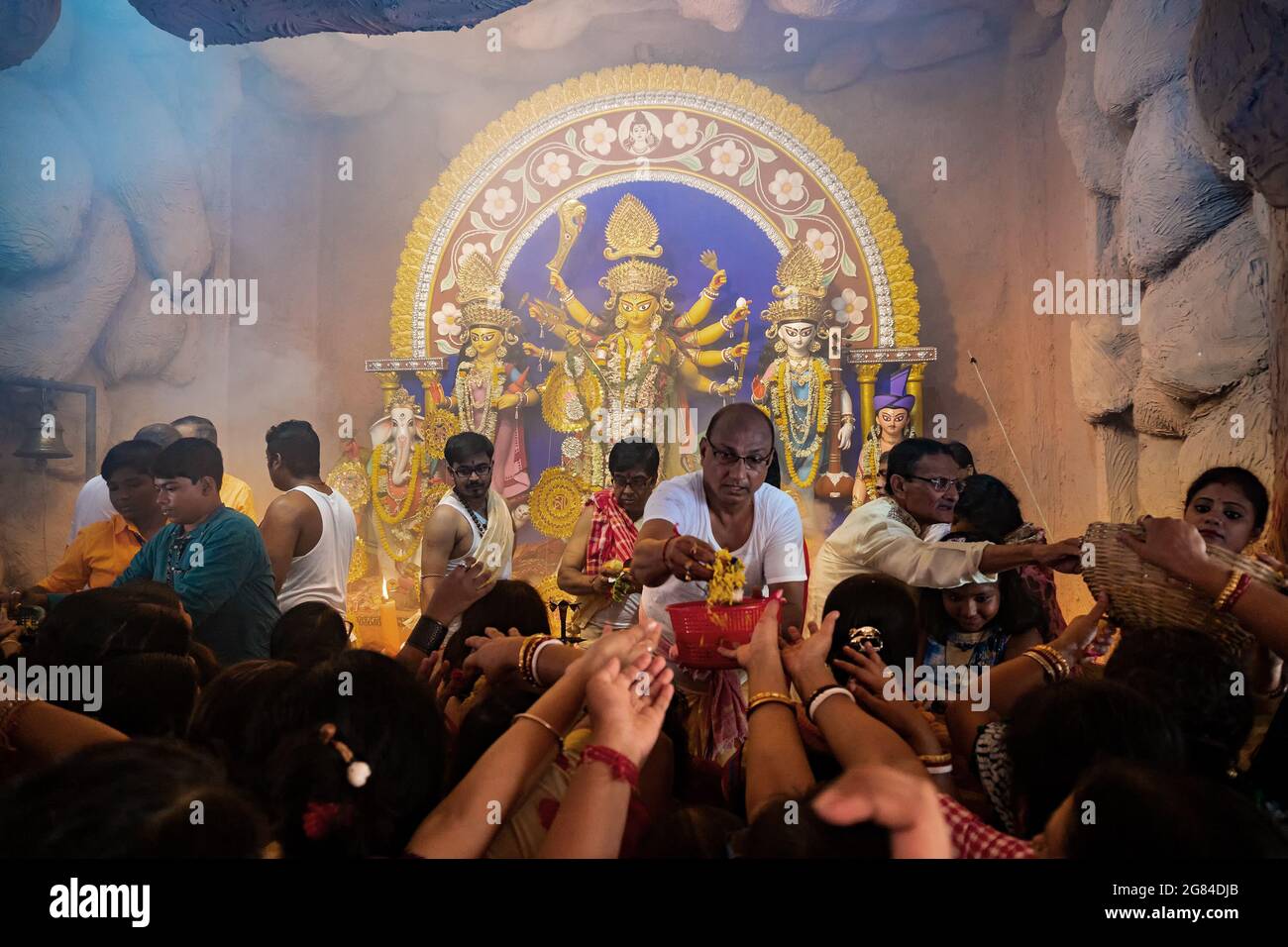 Kolkata, India-Ottobre 17,2018 : devoti femminili indù sari che si estendono le mani per ottenere fiori freschi per dedicarli alla dea Durga, chiamato Foto Stock