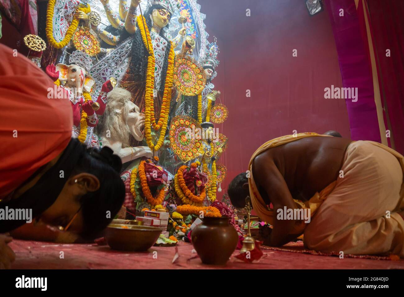 Kolkata, India - 16 ottobre 2018 : sacerdote indù e donna indiana che offre preghiera alla Dea Durga, festival Durga Puja rituale- sparato a luce colorata. Foto Stock