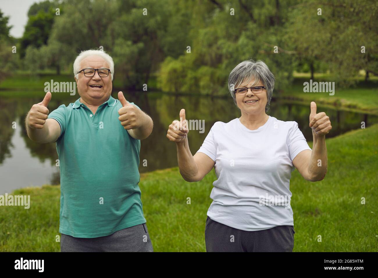 Ritratto di felice coppia senior che dà pollici dopo aver fatto esercizio sportivo in natura Foto Stock