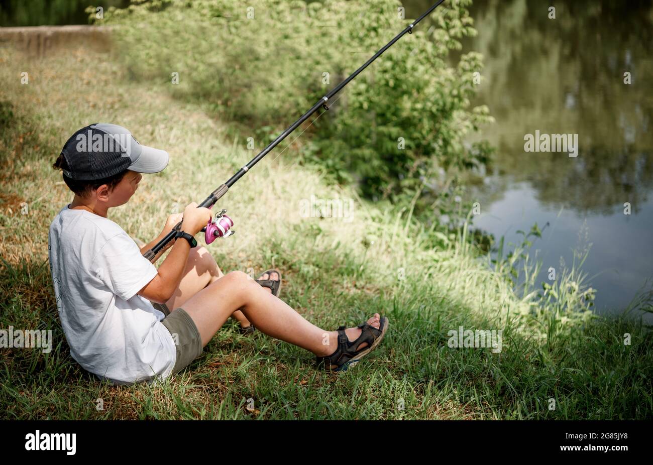 Un ragazzo che tiene una canna da pesca e la pesca nel lago, attività  estive e hobby per i bambini Foto stock - Alamy