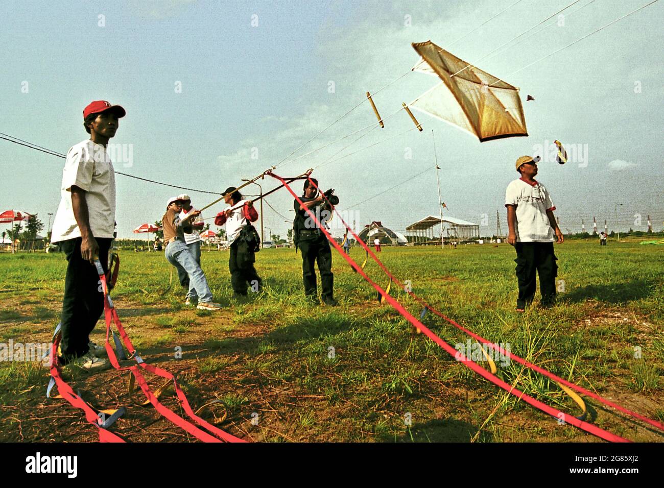 Gli uomini volano aquilone durante il 2004° Festival Internazionale di Kite di Giacarta che si è tenuto il 9-11 luglio a Karnaval (Carnival) Beach ad Ancol Dreamland, nel nord di Giacarta, Jakarta, Indonesia. Foto Stock