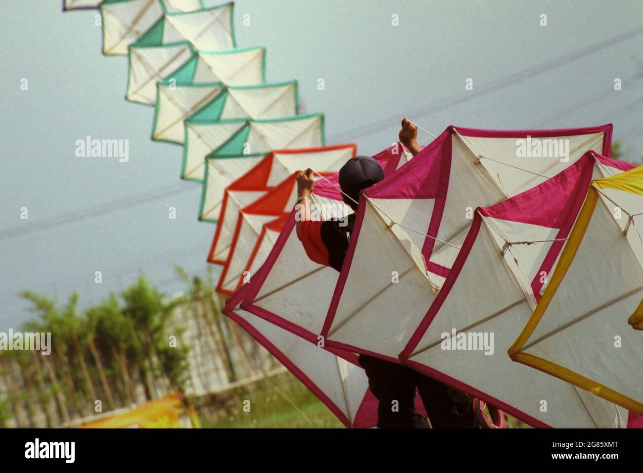 Un uomo che volava un aquilone gigante durante il Festival Internazionale del Kite di Giacarta del 2004 che si è tenuto il 9-11 luglio a Carnival Beach ad Ancol Dreamland, Jakarta Nord, Giacarta, Indonesia. Foto Stock