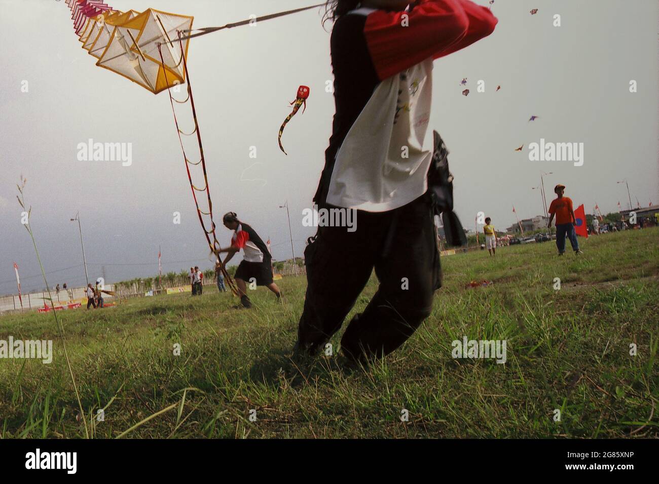 Uomini che volano un aquilone gigante durante il Festival Internazionale del Kite di Giacarta del 2004 che si è tenuto il 9-11 luglio a Carnival Beach ad Ancol Dreamland, Jakarta Nord, Giacarta, Indonesia. Foto Stock