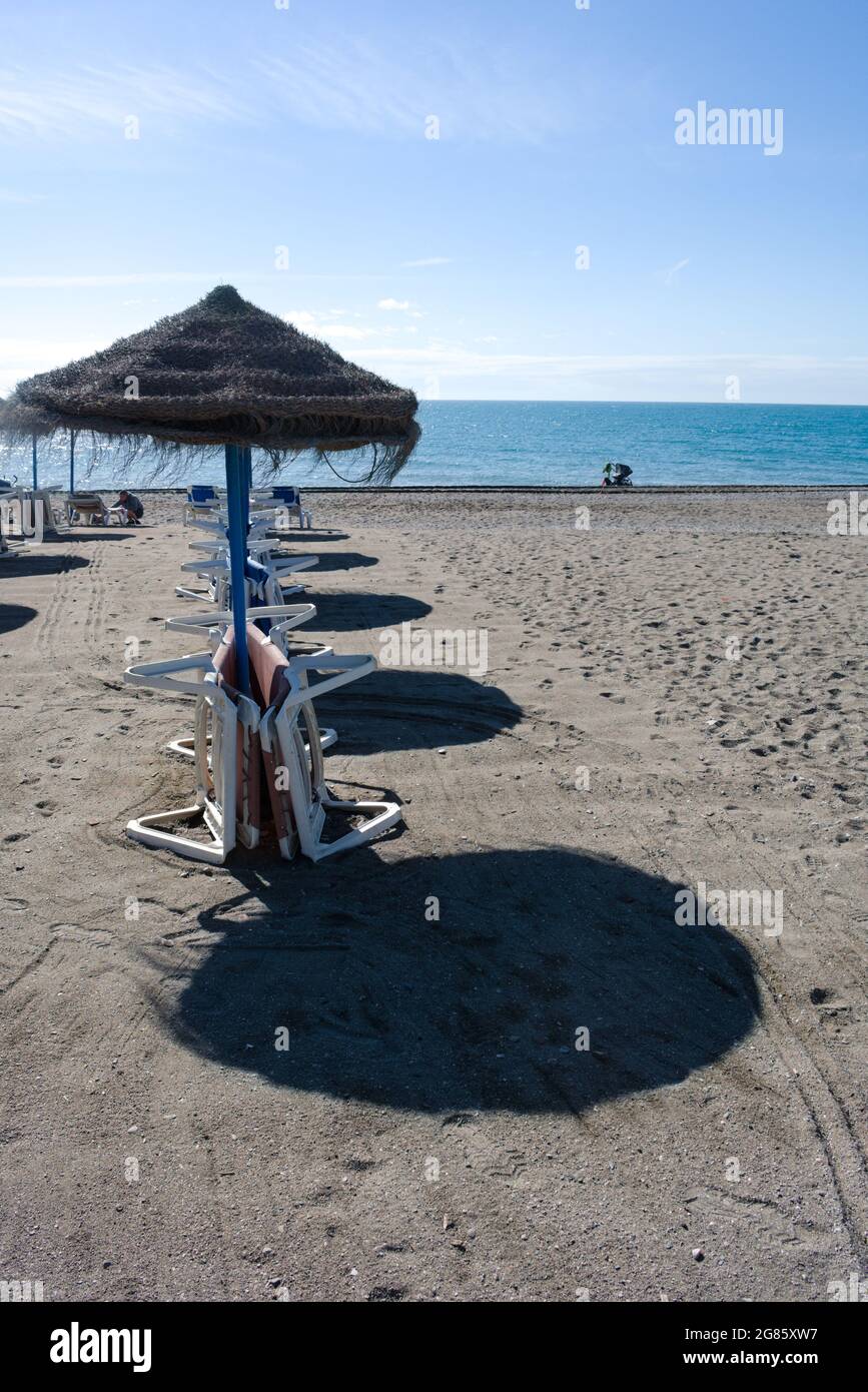 Spiaggia scena, Nerja, Spagna. Bella spiaggia di sabbia fiancheggiata da ombrelloni per ombra. Shot verticale. Cielo blu e spazio copie. Ombrelloni Foto Stock