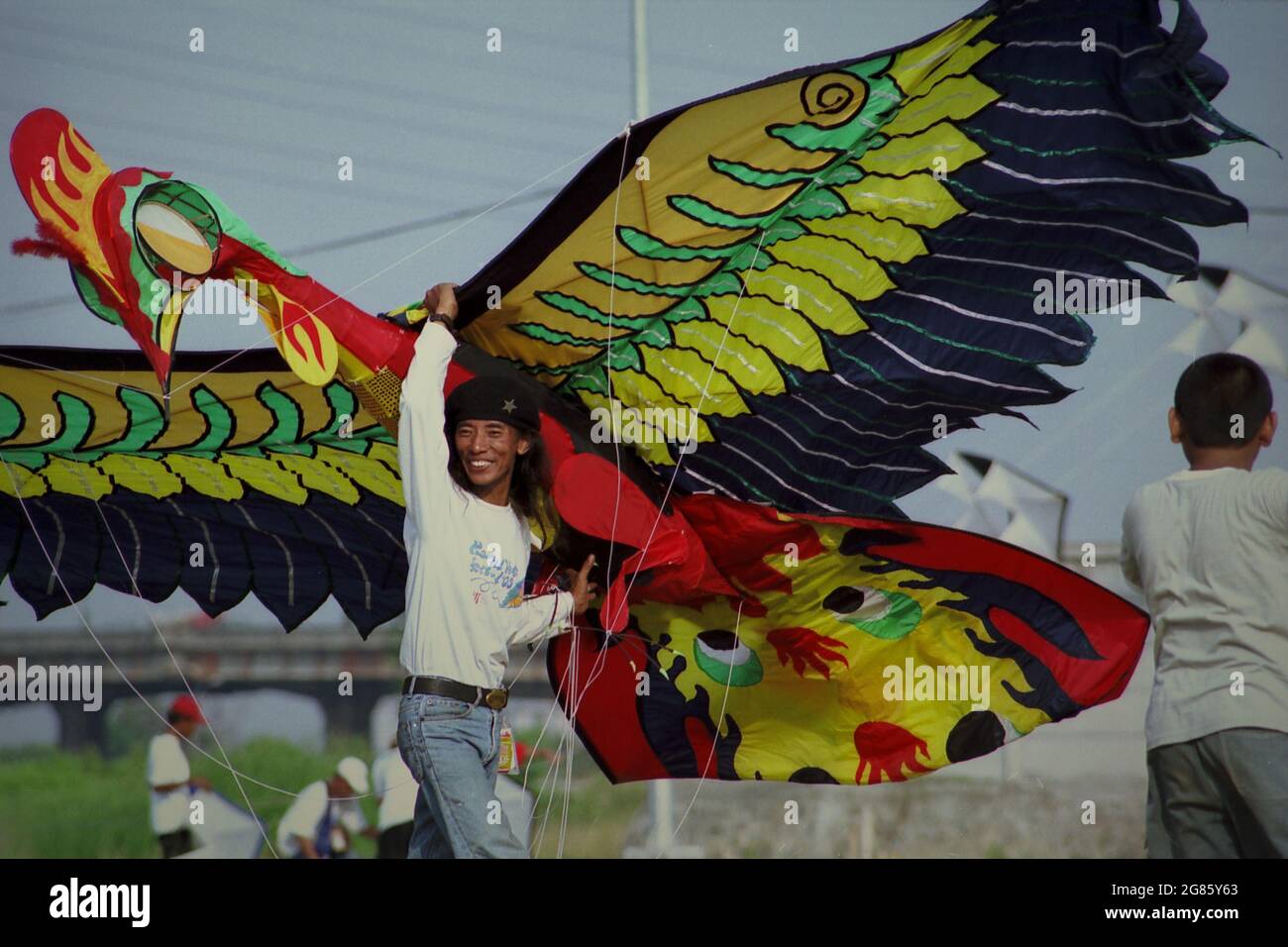Un partecipante che trasporta un aquilone gigante progettato per rappresentare una Garuda durante il Festival Internazionale del Kite di Giacarta del 2004 che si è tenuto il 9-11 luglio a Carnival Beach ad Ancol Dreamland, nel Nord di Giacarta, Giacarta, Indonesia. Foto Stock