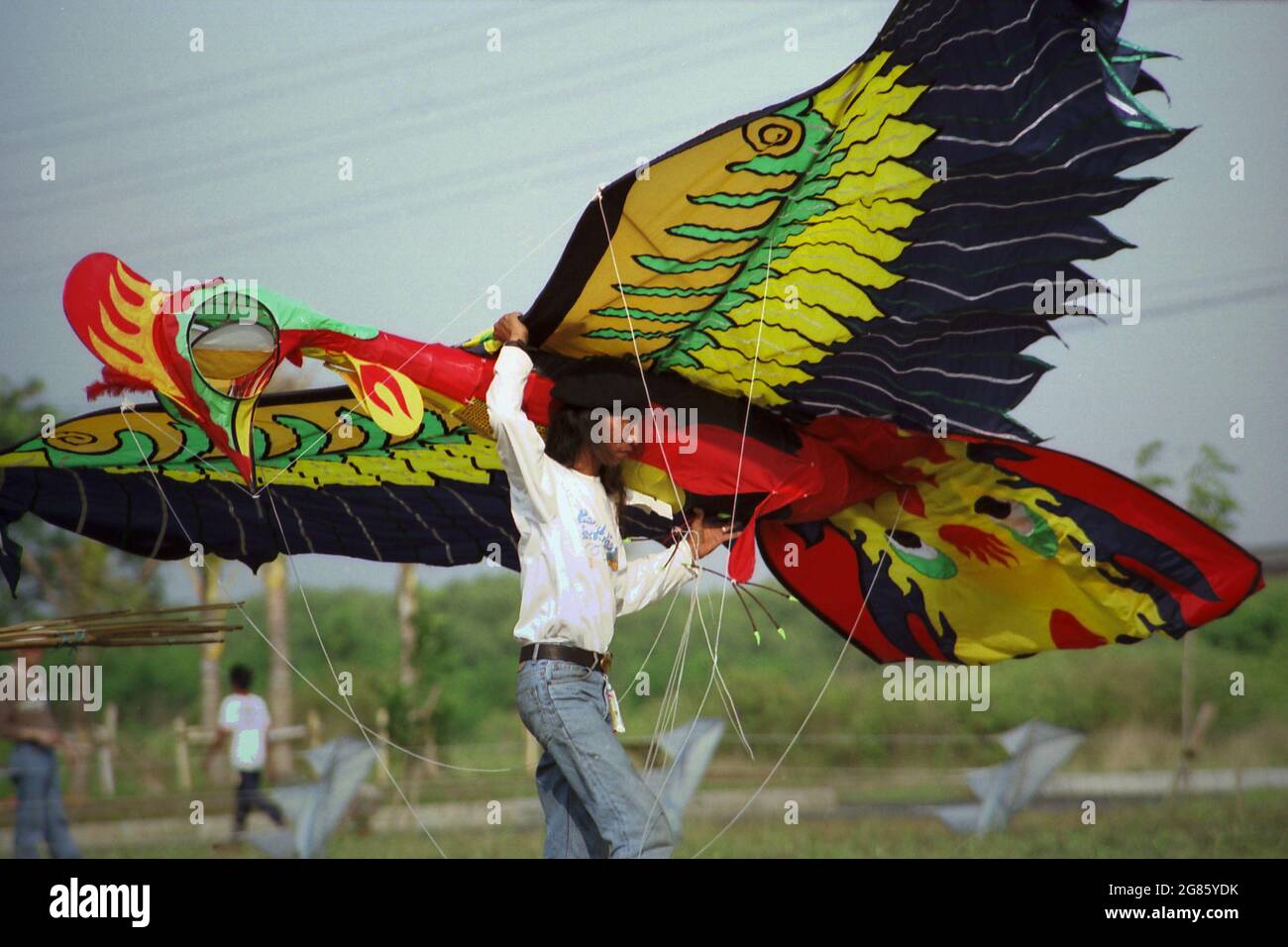 Un partecipante che trasporta un aquilone gigante progettato per rappresentare una Garuda durante il Festival Internazionale del Kite di Giacarta del 2004 che si è tenuto il 9-11 luglio a Carnival Beach ad Ancol Dreamland, nel Nord di Giacarta, Giacarta, Indonesia. Foto Stock