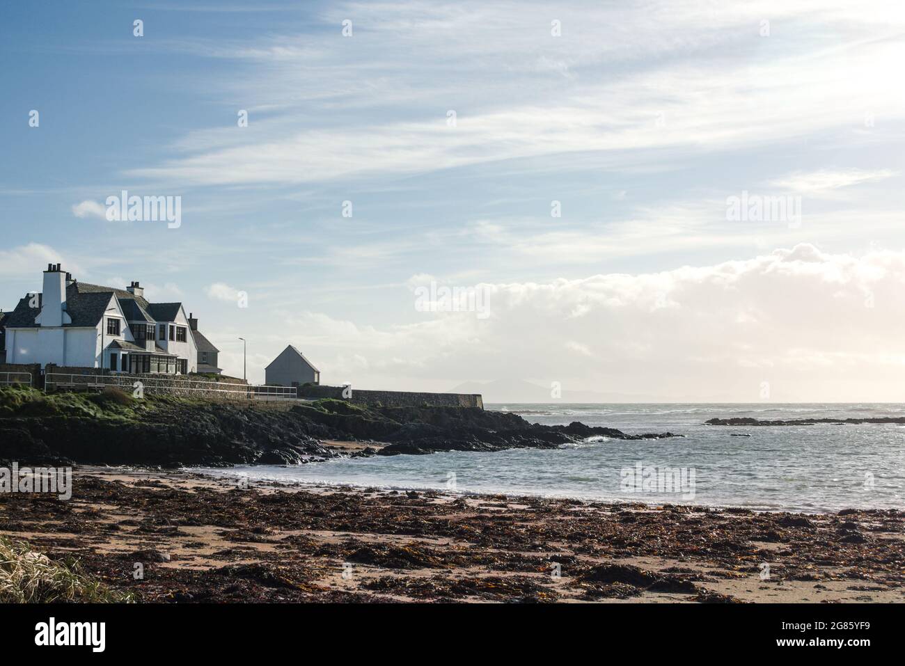 Rhoseigr, Anglesey, Galles. Vista panoramica invernale delle basse scogliere e di una baia con onde che si infrangono sulla spiaggia. Cielo blu e spazio copia. Foto Stock