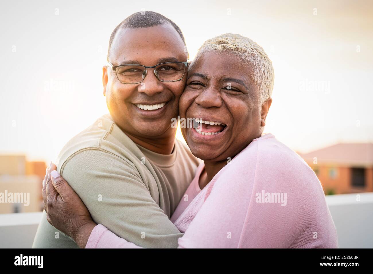 Felice coppia latina anziana che ha un momento romantico abbracciando sul tetto Durante il tramonto - gli anziani amano il concetto Foto Stock