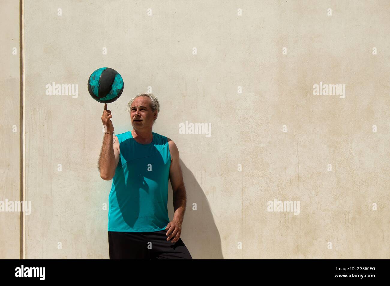 ritratto di uomo maturo sul campo di pallacanestro di strada contro un muro che gioca con una palla Foto Stock
