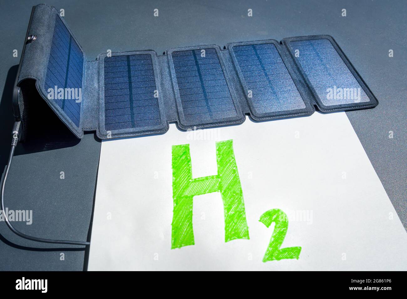 Concetto di idrogeno verde. Pannello solare collegato al testo H2, che simboleggia la generazione di idrogeno da energia solare senza combustibili fossili. Foto Stock