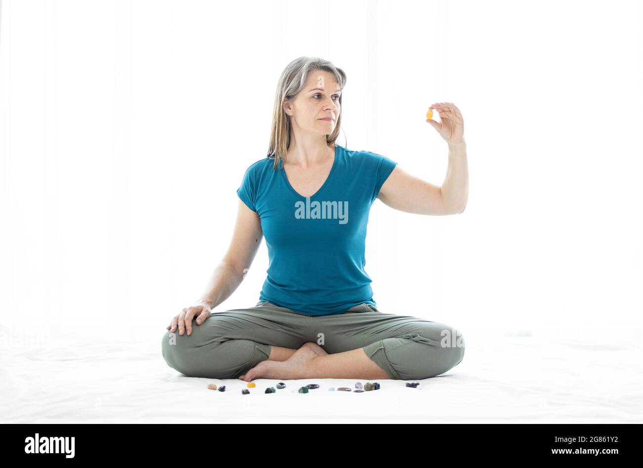 Meditationg donna di mezza età con cristalli Foto Stock