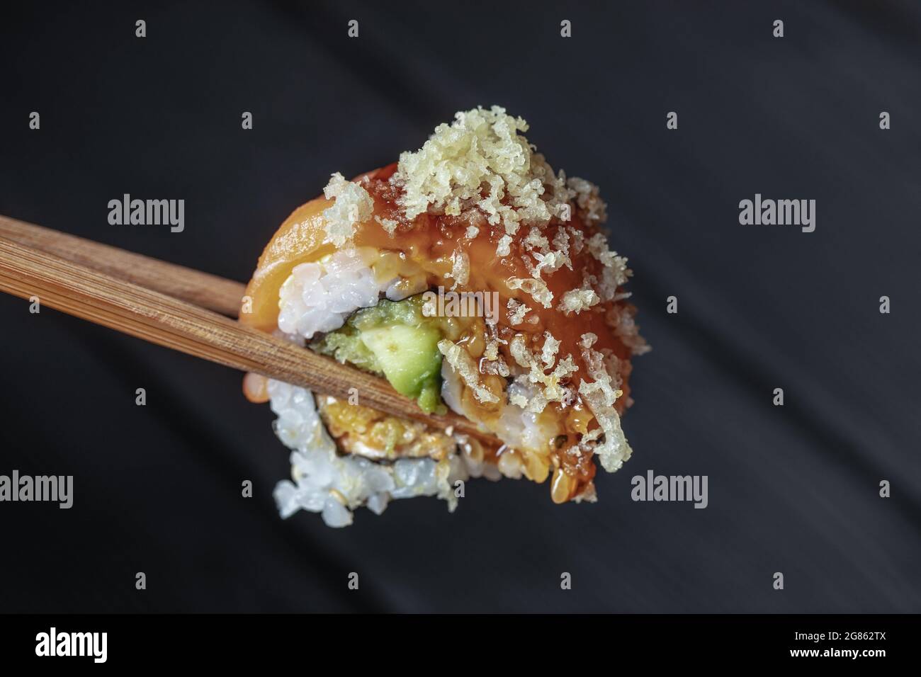 primo piano di bacchette che prendono parte al sushi roll on il ristorante da tavolo / mangiare sushi roll utilizzando bastoncini Foto Stock