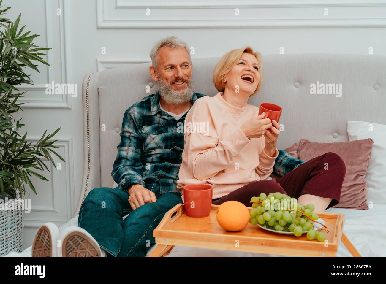 marito e moglie hanno la colazione a letto con caffè e frutta Foto Stock