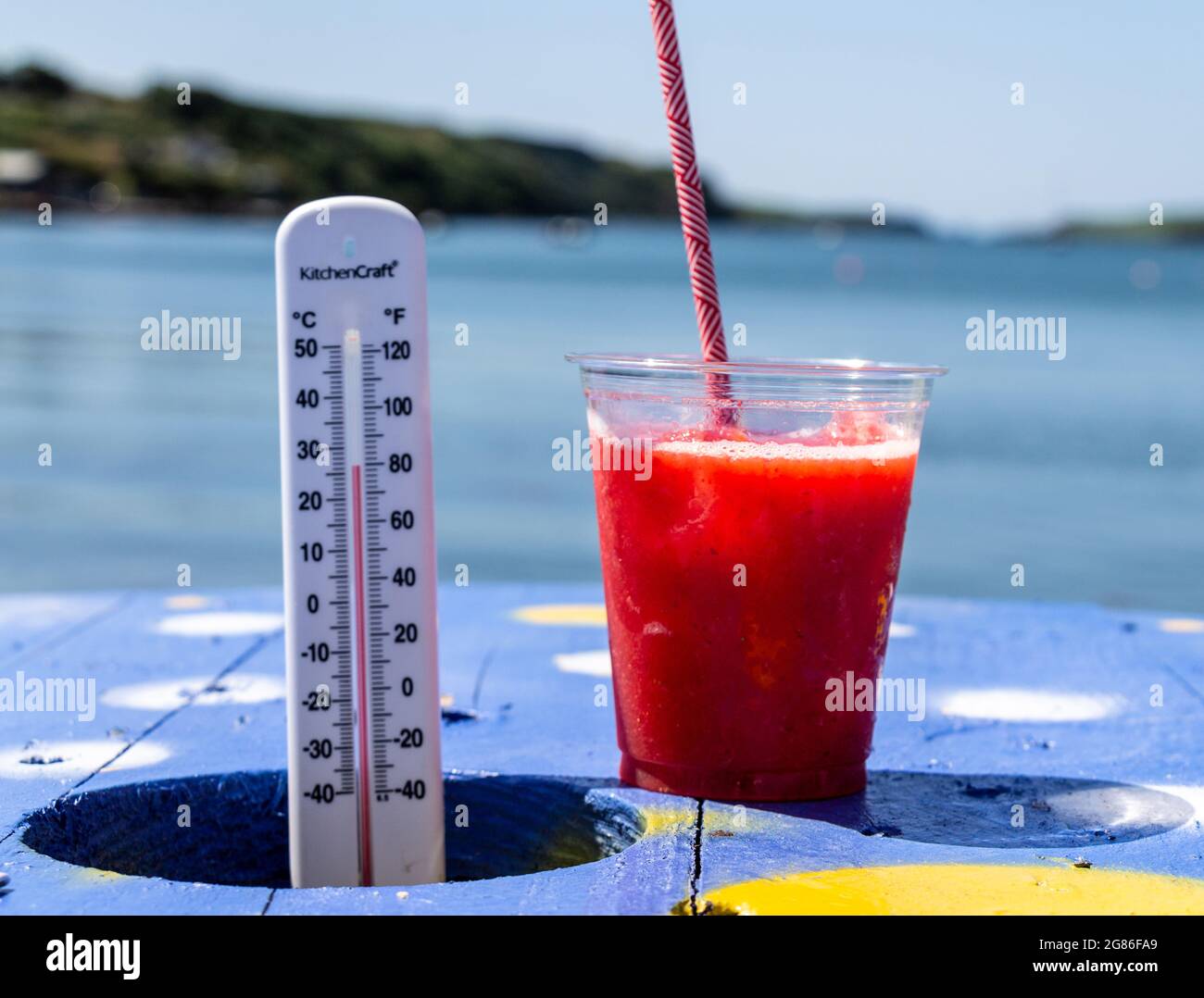 Termometro di temperatura accanto a ghiaccio bevanda fredda che mostra molto caldo estate giorno. Foto Stock