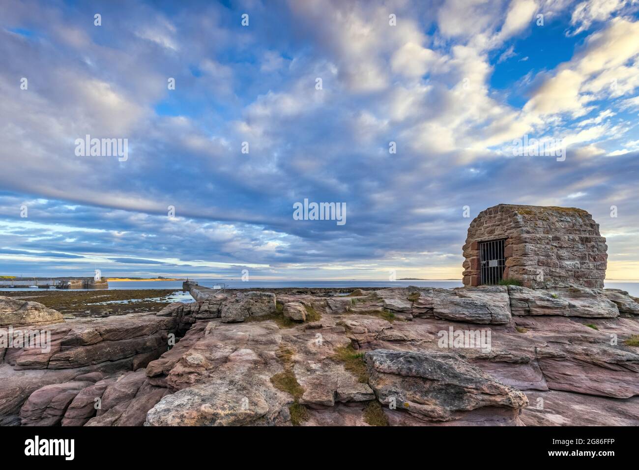La Powder House a Seahouses sulla costa del Northumberland, con un suggestivo cielo mattutino. Foto Stock