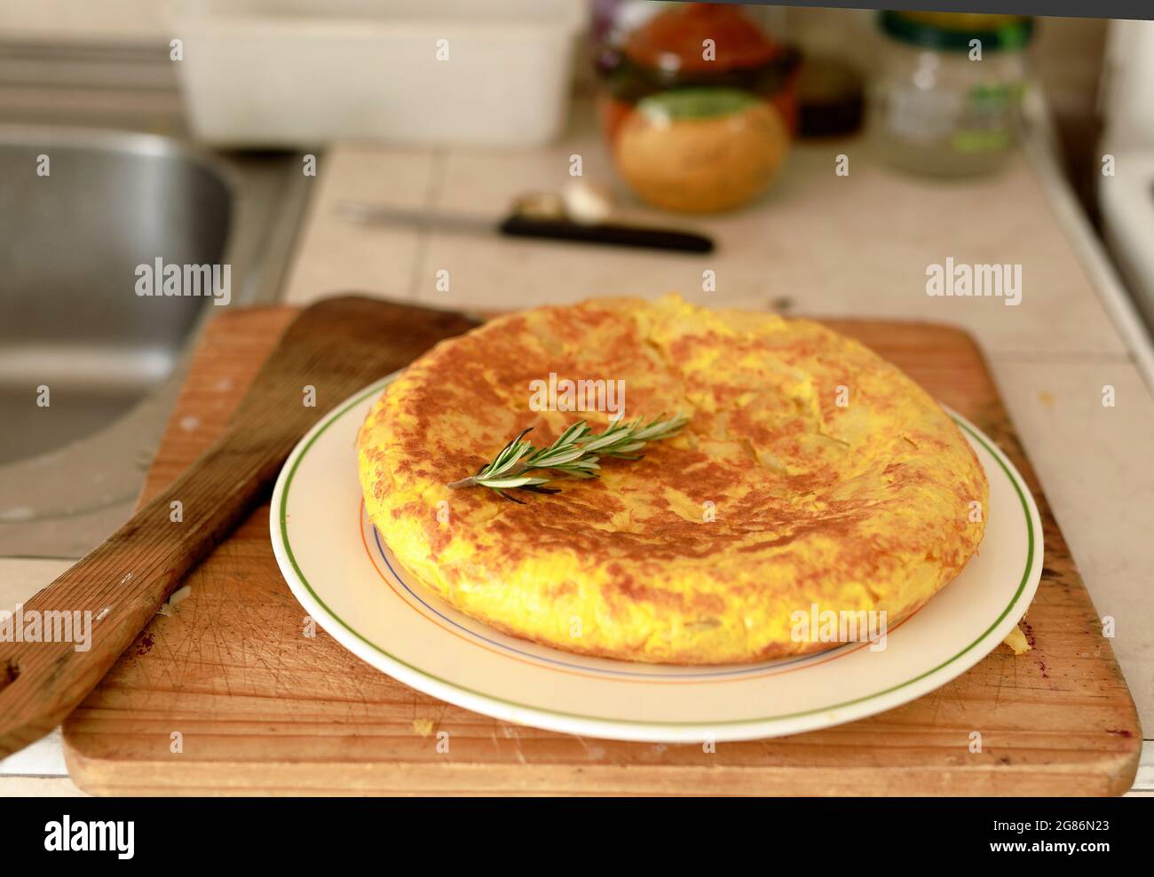 Omelette spagnole fatte in casa su un piatto bianco, sullo sfondo di un tavolo di legno. Foto Stock
