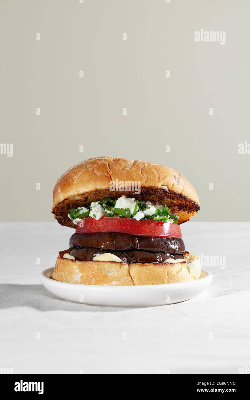 Hamburger con panino vegano con melanzane arrostite, formaggio feta e coriandolo. Concetto di cibo basato su piante Foto Stock