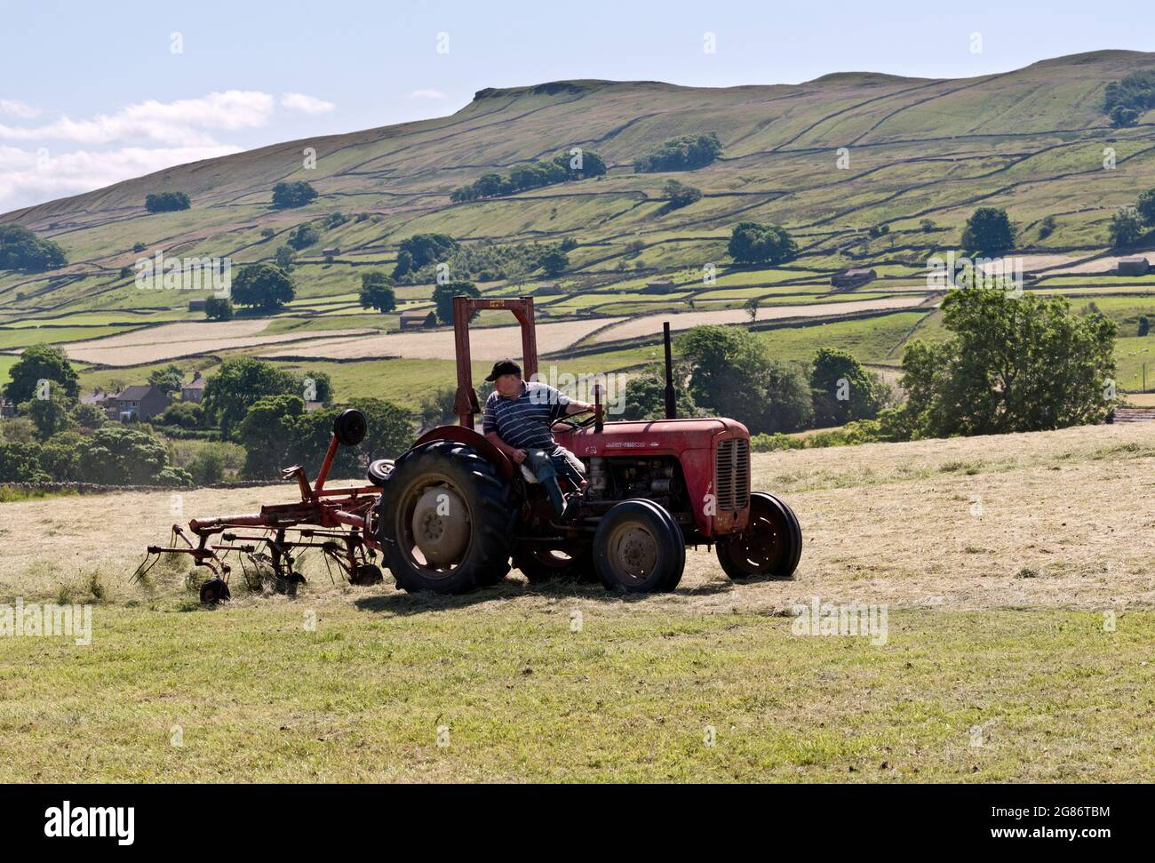 Hawes, Yorkshire Dales National Park, Regno Unito. L'attrezzo sul trattore gira l'erba falciata. Foto Stock