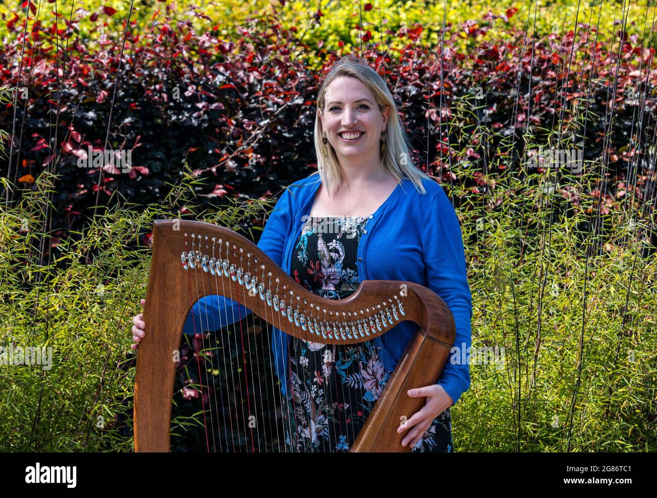 Haddington, East Lothian, Scozia, Regno Unito, 17 luglio 2021. L'arpista celtica Ailie Robertson suona nel giardino murato di Amisfield: Un concerto socialmente distanziato si svolge nel giardino murato gestito da volontari, uno dei più grandi della Scozia. Ailie Robertson è un premiato compositore e performer che suona musica tradizionale e contemporanea arpa Foto Stock