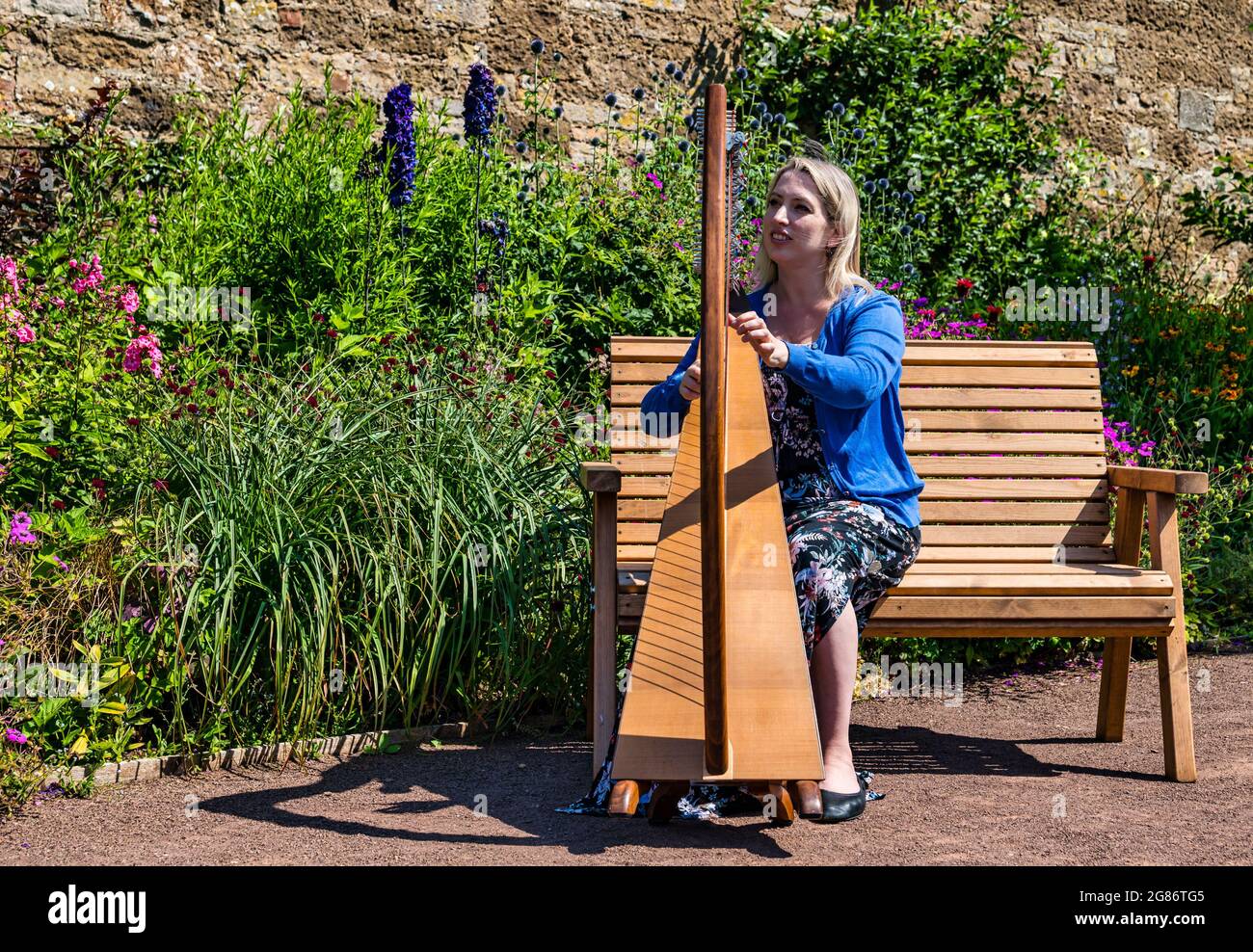 Haddington, East Lothian, Scozia, Regno Unito, 17 luglio 2021. L'arpista celtica Ailie Robertson suona nel giardino murato di Amisfield: Un concerto socialmente distanziato si svolge nel giardino murato gestito da volontari, uno dei più grandi della Scozia. Ailie Robertson è un premiato compositore e performer che suona musica tradizionale e contemporanea arpa Foto Stock