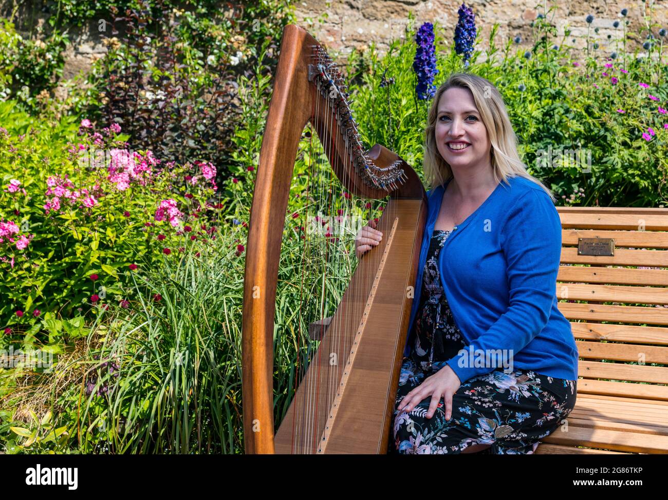 Haddington, East Lothian, Scozia, Regno Unito, 17 luglio 2021. L'arpista celtica Ailie Robertson suona nel giardino murato di Amisfield: Un concerto socialmente distanziato si svolge nel giardino murato gestito da volontari, uno dei più grandi della Scozia. Ailie Robertson è un premiato compositore e performer che suona musica tradizionale e contemporanea arpa Foto Stock