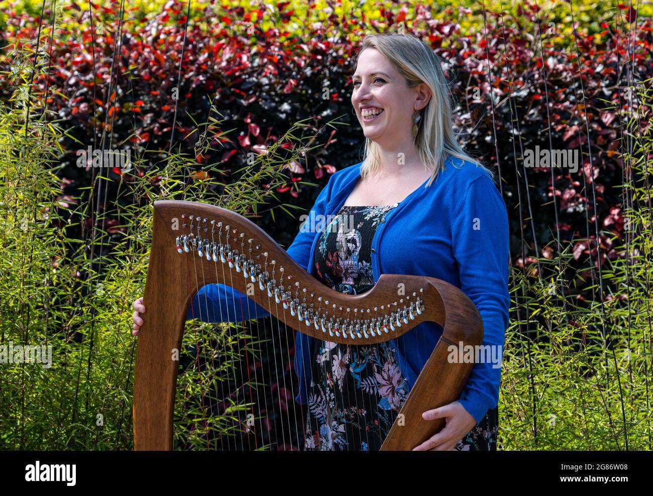 Haddington, East Lothian, Scozia, Regno Unito, 17 luglio 2021. L'arpista celtica Ailie Robertson suona nel giardino murato di Amisfield: Un concerto socialmente distanziato si svolge nel giardino murato gestito da volontari, uno dei più grandi della Scozia. Ailie Robertson è un premiato compositore e performer che suona musica tradizionale e contemporanea arpa Foto Stock