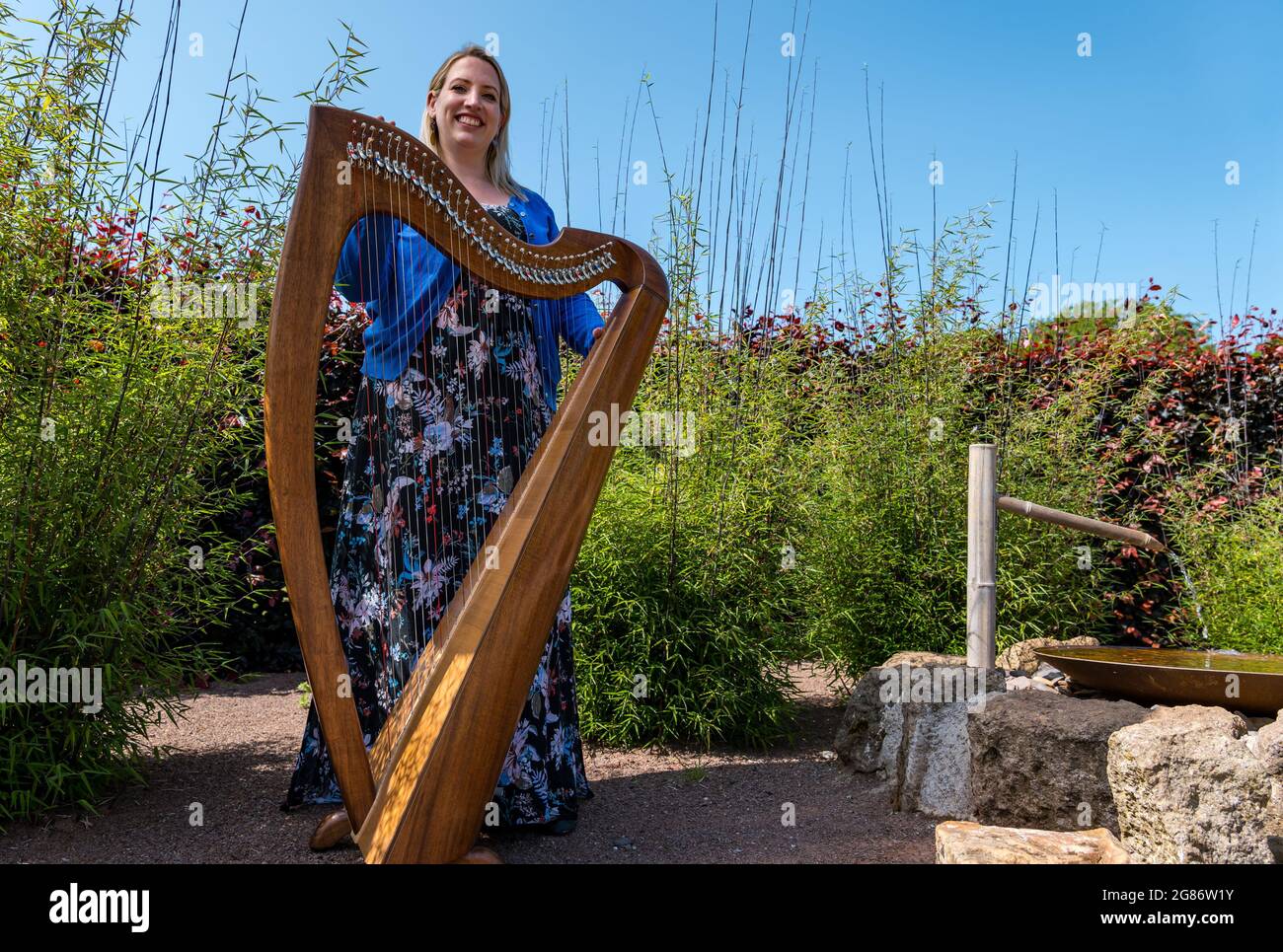 Haddington, East Lothian, Scozia, Regno Unito, 17 luglio 2021. L'arpista celtica Ailie Robertson suona nel giardino murato di Amisfield: Un concerto socialmente distanziato si svolge nel giardino murato gestito da volontari, uno dei più grandi della Scozia. Ailie Robertson è un premiato compositore e performer che suona musica tradizionale e contemporanea arpa Foto Stock