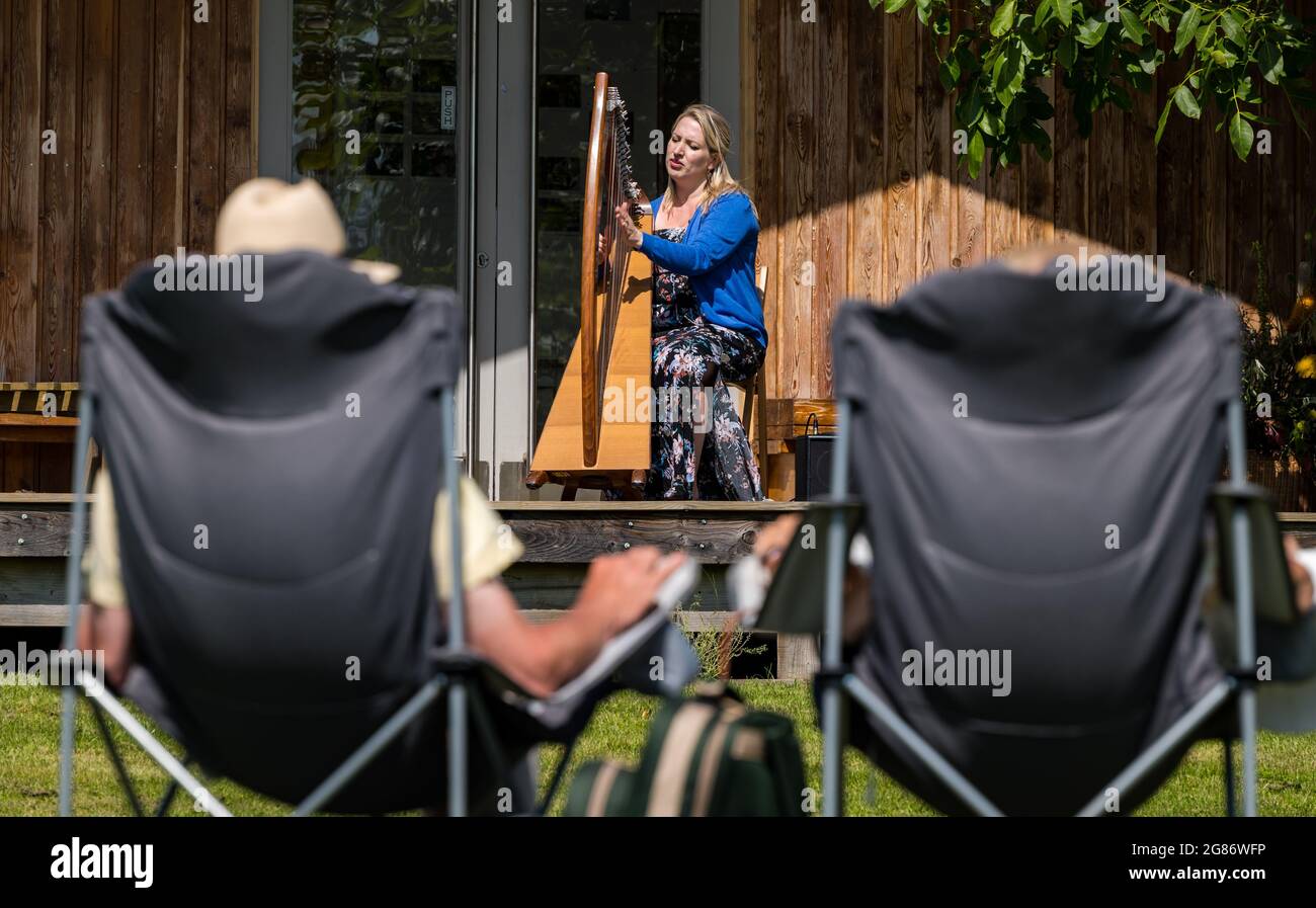 Haddington, East Lothian, Scozia, Regno Unito, 17 luglio 2021. L'arpista celtica Ailie Robertson suona nel giardino murato di Amisfield: Un concerto socialmente distanziato si svolge nel giardino murato gestito da volontari, uno dei più grandi della Scozia. Ailie Robertson è un premiato compositore e performer che suona musica tradizionale e contemporanea arpa Foto Stock