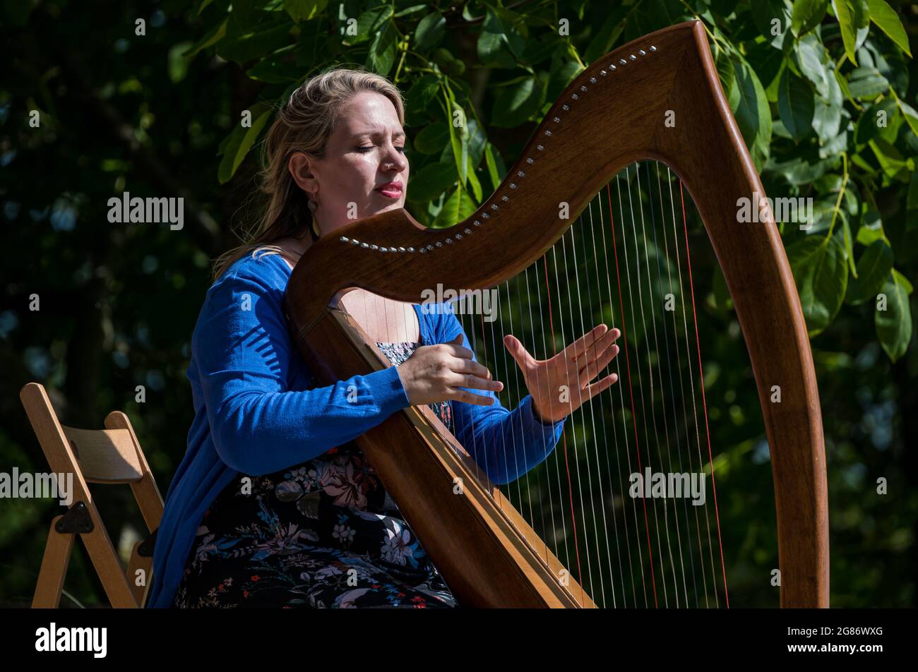 Haddington, East Lothian, Scozia, Regno Unito, 17 luglio 2021. L'arpista celtica Ailie Robertson suona nel giardino murato di Amisfield: Un concerto socialmente distanziato si svolge nel giardino murato gestito da volontari, uno dei più grandi della Scozia. Ailie Robertson è un premiato compositore e performer che suona musica tradizionale e contemporanea arpa Foto Stock