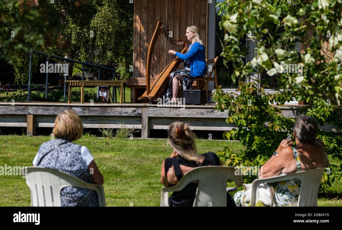Haddington, East Lothian, Scozia, Regno Unito, 17 luglio 2021. L'arpista celtica Ailie Robertson suona nel giardino murato di Amisfield: Un concerto socialmente distanziato si svolge nel giardino murato gestito da volontari, uno dei più grandi della Scozia. Ailie Robertson è un premiato compositore e performer che suona musica tradizionale e contemporanea arpa Foto Stock
