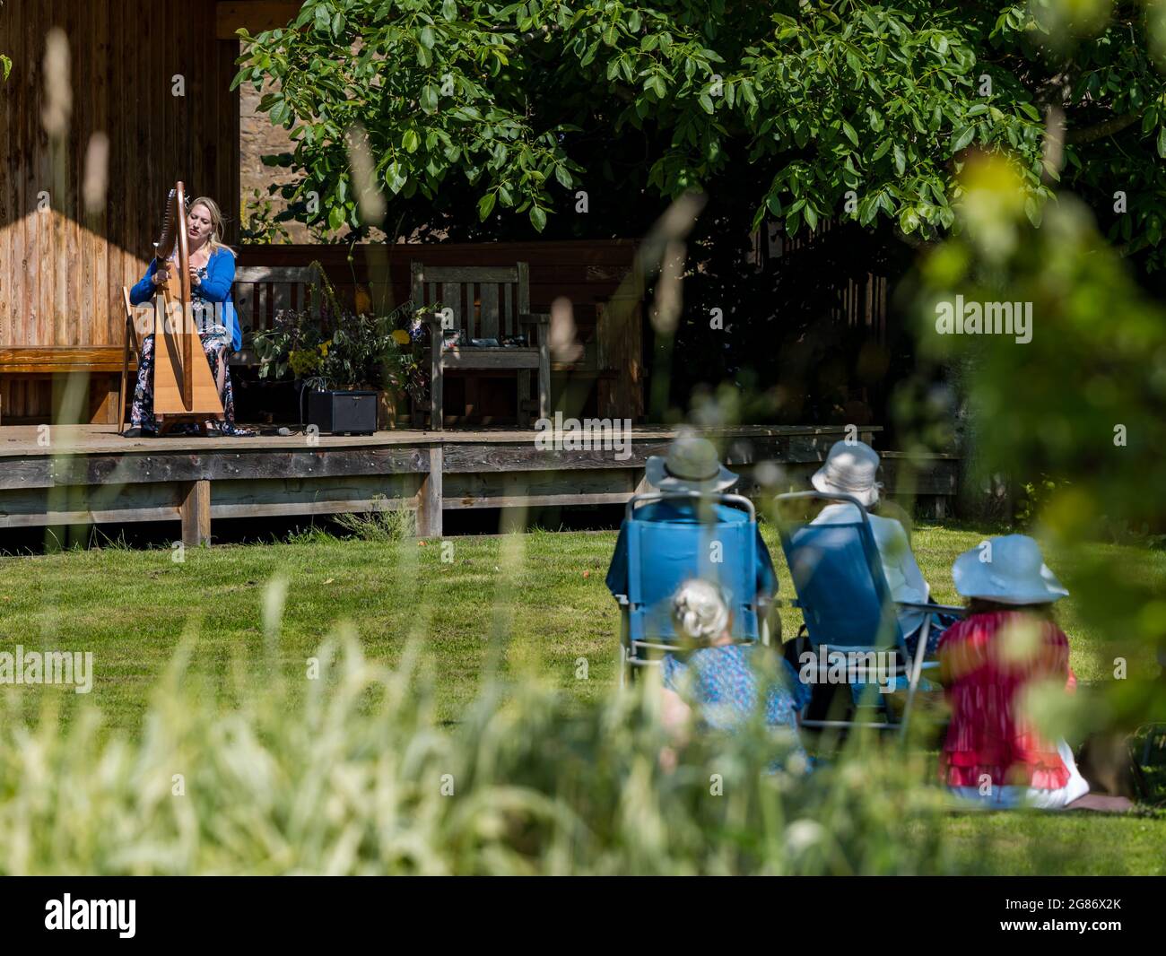 Haddington, East Lothian, Scozia, Regno Unito, 17 luglio 2021. L'arpista celtica Ailie Robertson suona nel giardino murato di Amisfield: Un concerto socialmente distanziato si svolge nel giardino murato gestito da volontari, uno dei più grandi della Scozia. Ailie Robertson è un premiato compositore e performer che suona musica tradizionale e contemporanea arpa Foto Stock