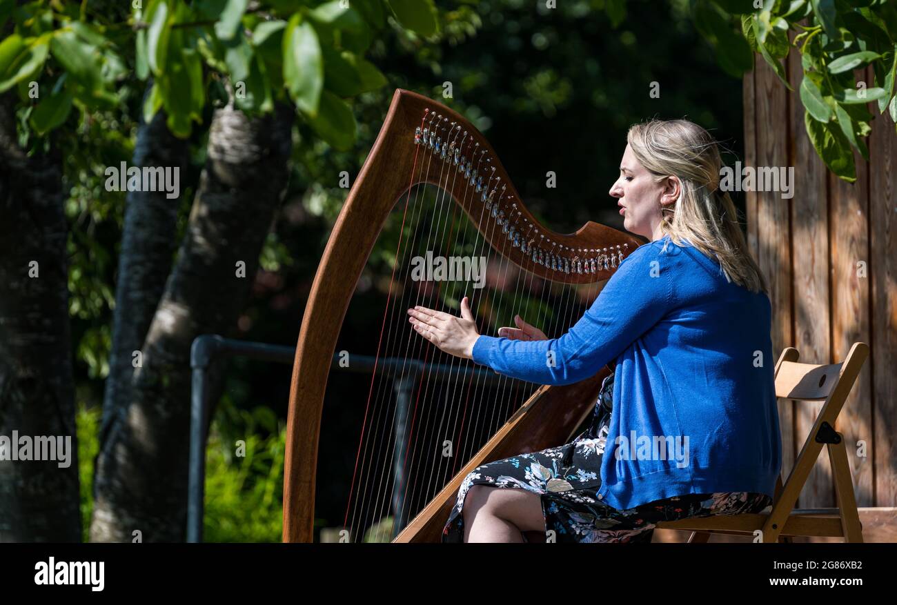 Haddington, East Lothian, Scozia, Regno Unito, 17 luglio 2021. L'arpista celtica Ailie Robertson suona nel giardino murato di Amisfield: Un concerto socialmente distanziato si svolge nel giardino murato gestito da volontari, uno dei più grandi della Scozia. Ailie Robertson è un premiato compositore e performer che suona musica tradizionale e contemporanea arpa Foto Stock